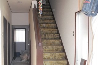 【施工中】階段の絨毯を捲（めく）った状態です。この上からリフォーム用の階段材を、微妙にサイズの異なる既設の階段に合わせて、階段材を一枚一枚、カンナなどで削って貼っていきます。