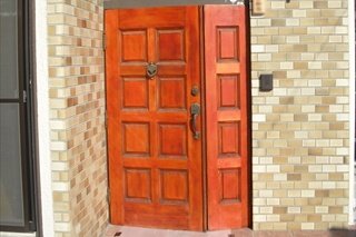 【施工前】長年の日焼けで色あせ始めた木製の玄関ドアでした。